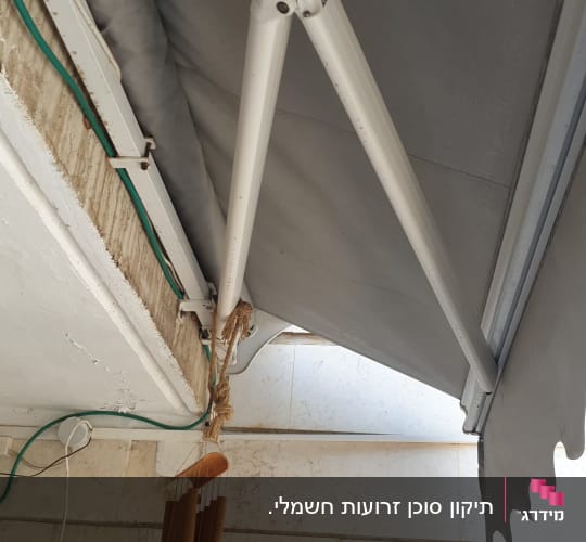 סוכך אפור עם זרועות מתכת לבנות על קיר